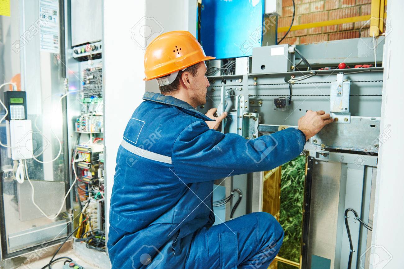 electrician worker adjusting equipment in elevator lift